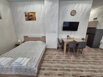 a hotel room with two beds and a table and a television at Студио Лазур Поморие in Pomorie