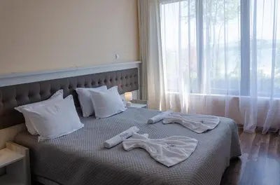 a bedroom with a bed with two towels on it at Green Paradise Deluxe Apartments in Primorsko