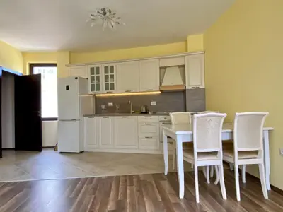 a kitchen with white cabinets and a table and chairs at Green Paradise Deluxe Apartments in Primorsko