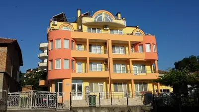 a yellow and orange building with a balcony at Zlatevi Guest House in Obzor