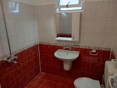 a red tiled bathroom with a toilet and a sink at Zlatevi Guest House in Obzor
