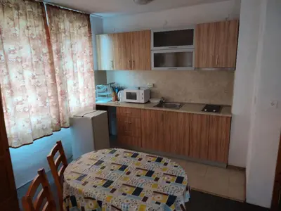 a small kitchen with a table and a microwave at Zlatevi Guest House in Obzor