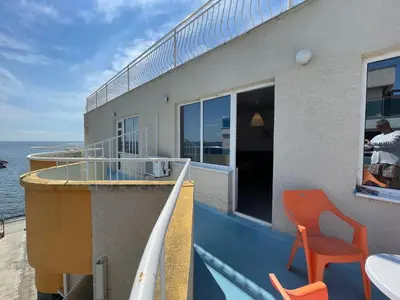 a balcony with a table and a orange chair at Apartments Panorama Ravda in Ravda