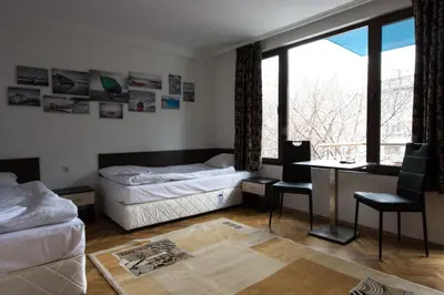 a bedroom with two beds and a desk and a window at Guest Rooms Old Captain in Burgas City