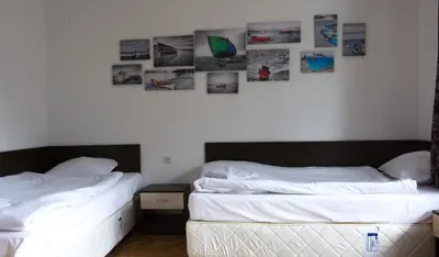 two beds in a bedroom with pictures on the wall at Guest Rooms Old Captain in Burgas City