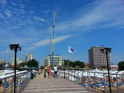 a boardwalk with a flag and people on it at Menada Crystal Park Apartments in Sunny Beach