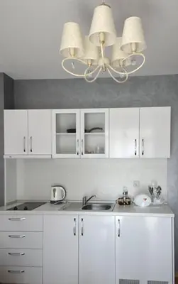 a kitchen with white cabinets and a chandelier at Stela Apartments in Obzor