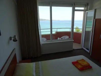 a bedroom with a bed and a view of the ocean at Dobrevi Guest House in Primorsko