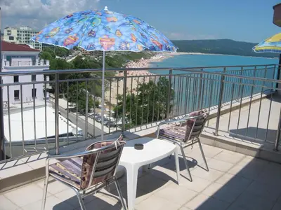 a balcony with two chairs and a table and an umbrella at Dobrevi Guest House in Primorsko