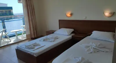 two beds in a hotel room with a window at Hotel Shipka Beach in Sunny Beach