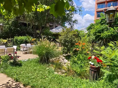 a garden with flowers and a table and chairs at Hotel Shipka Beach in Sunny Beach