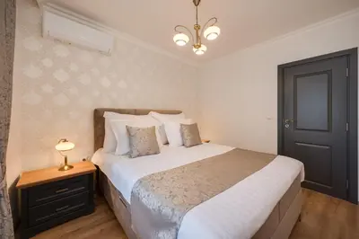 a bedroom with a large bed with white sheets and a black door at Prestige Central Apartments in Varna City