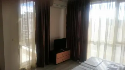 a bedroom with a bed and a television and a window at Casa del Sol Apartments in Sunny Beach