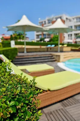 a pool with lounge chairs and umbrellas on a patio at Apartments in Sunny Island Complex in Chernomorets