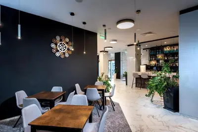 a restaurant with wooden tables and white chairs at Best Western PLUS Premium Inn in Sunny Beach