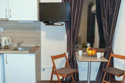 a kitchen with a sink and a table with a television at Flora Beach Apartaments in Burgas City