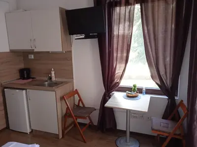 a kitchen with a table and a sink and a window at Flora Beach Apartaments in Burgas City