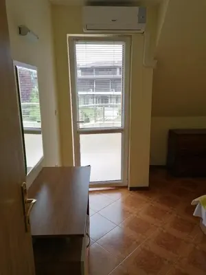 an empty room with a table and two windows at Villa Krisia Apartments in Sozopol