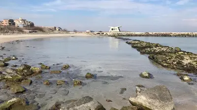 a beach with rocks in the water and a lighthouse at Beach Apartments Pomorie in Pomorie
