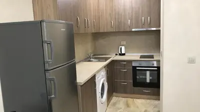 a kitchen with a stainless steel refrigerator and wooden cabinets at Beach Apartments Pomorie in Pomorie