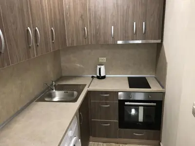 a small kitchen with wooden cabinets and a sink at Beach Apartments Pomorie in Pomorie