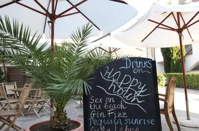 a sign that says drinks on my happy nightsaw on the beach in the backyard at NLV Seaside Apartments in Sunny Beach