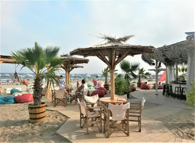 a patio with tables and chairs on the beach at NLV Seaside Apartments in Sunny Beach