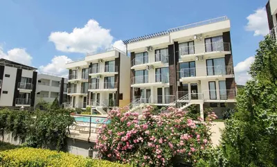 an apartment building with a swimming pool and flowers at NLV Seaside Apartments in Sunny Beach