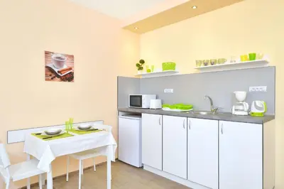 a kitchen with white cabinets and a white table and chairs at Central studio 1 in Burgas City