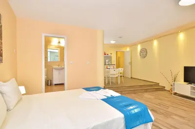 a bedroom with a white bed and a living room at Central studio #2 in Burgas City