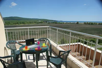 a balcony with a table with a laptop on it at Pearl Sunshine Appartments in Primorsko