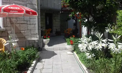 a garden with a red umbrella and some flowers at Kraybrezhna 3 in Pomorie