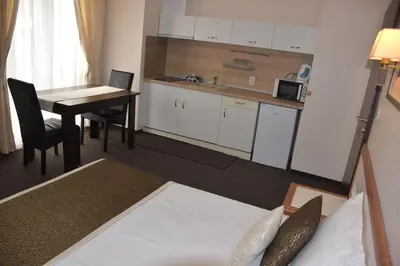 a room with a bed and a table and a kitchen at Guest House SG-BROTHERS in Obzor