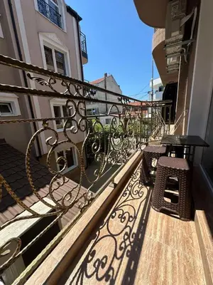 a balcony with two benches and a table on a building at Dracena Guesthouse in Ravda