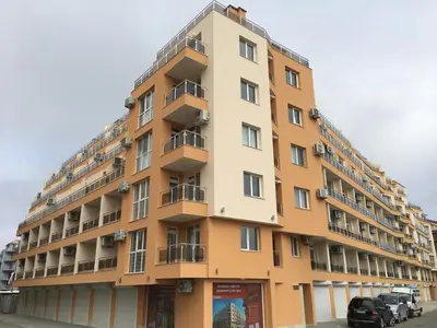 a tall yellow building with balconies on a street at Studio Martin in Pomorie