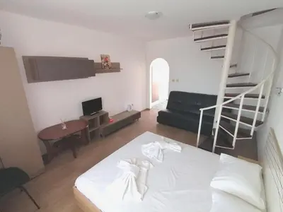 a bedroom with a white bed and a spiral staircase at Siana House in Ravda