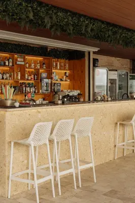 a bar with four white chairs in front of it at Rich Collective in Nesebar
