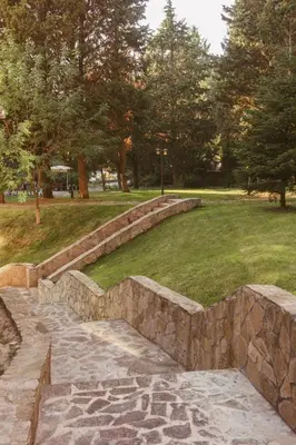 a stone retaining wall in a park with trees at Rich Collective in Nesebar
