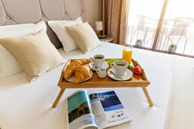 a coffee table with croissants and coffee cups on a bed at Burgas Beach Resort Apartments in Burgas City