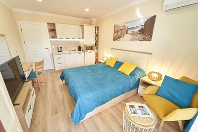 a bedroom with a blue bed and a kitchen at Burgas Beach Resort Apartments in Burgas City