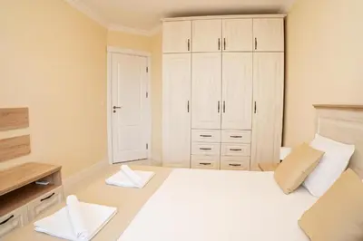 a bedroom with a white bed and white cabinets at Burgas Beach Resort Apartments in Burgas City