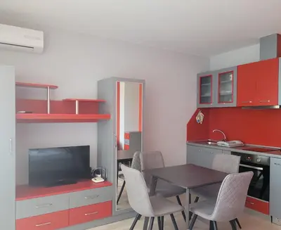 a kitchen with a table and chairs and red cabinets at Sirena Holidays in Ravda