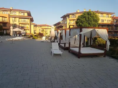 a courtyard with beds and chairs in front of buildings at Private Apartment in Star Dreams Complex in Sveti Vlas