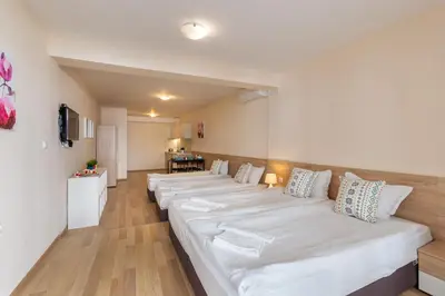 a row of white beds in a room at Apartments Flora in Burgas City
