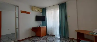 a hotel room with a television and green curtains at Rooms Via Maris in Sozopol