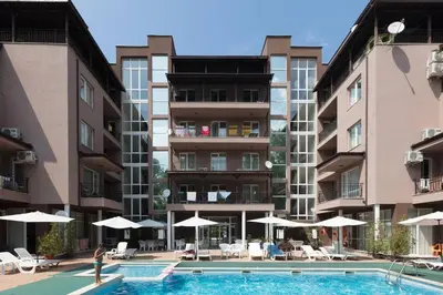 a person standing near a swimming pool in front of buildings at Santa Sofia Studio in Sunny Beach