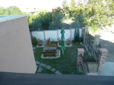 a backyard with an umbrella and chairs and a fence at Aleksandrovo Apartments in Aleksandrovo