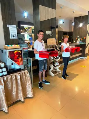 a man is holding a red box in a store at Aparthotel Hotel Prestige City II in Primorsko