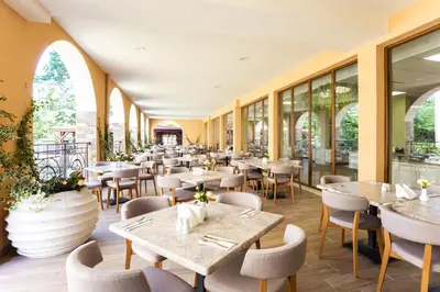 a restaurant with tables and chairs and windows at Festa Via Pontica in Pomorie