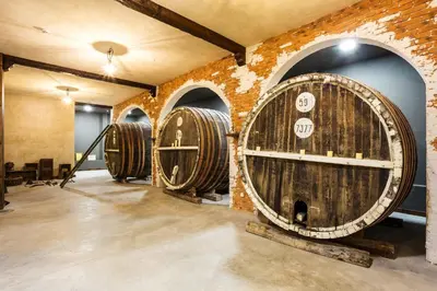 a row of wine barrels in a room with a brick wall at Festa Via Pontica in Pomorie